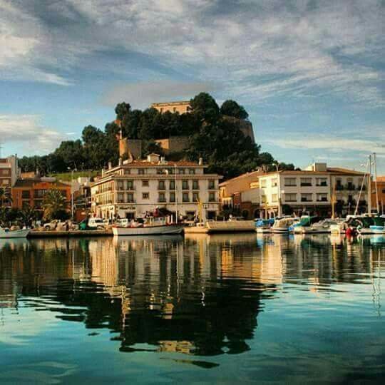 The port of Dénia reflected in still water, the castle on the hill above
