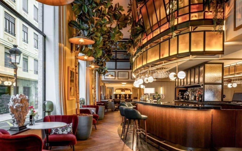 A hotel lounge bar in Valencia with velvet chairs, brass lamps and hanging plants