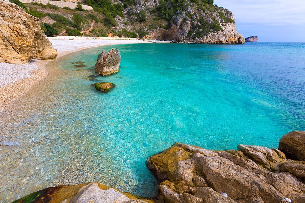 Crystal-clear turquoise water and white pebbles in a cove near Jávea