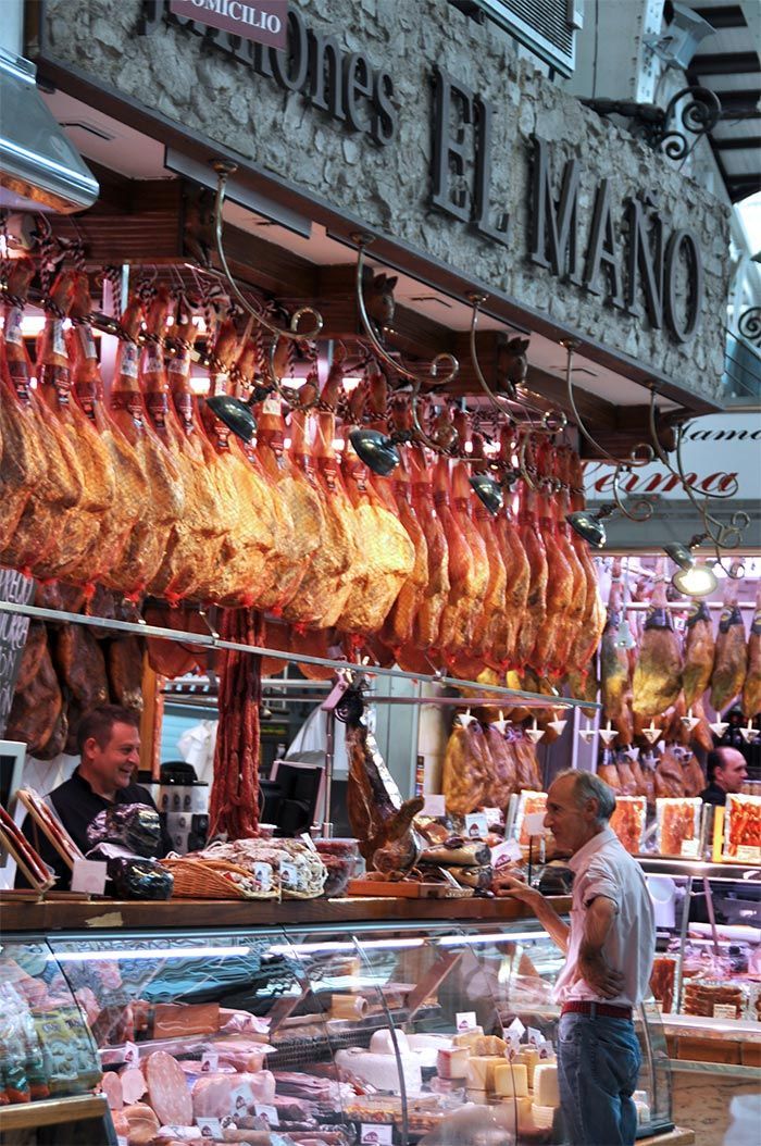 Hams hanging over a charcuterie stall in the Mercado Central of Valencia