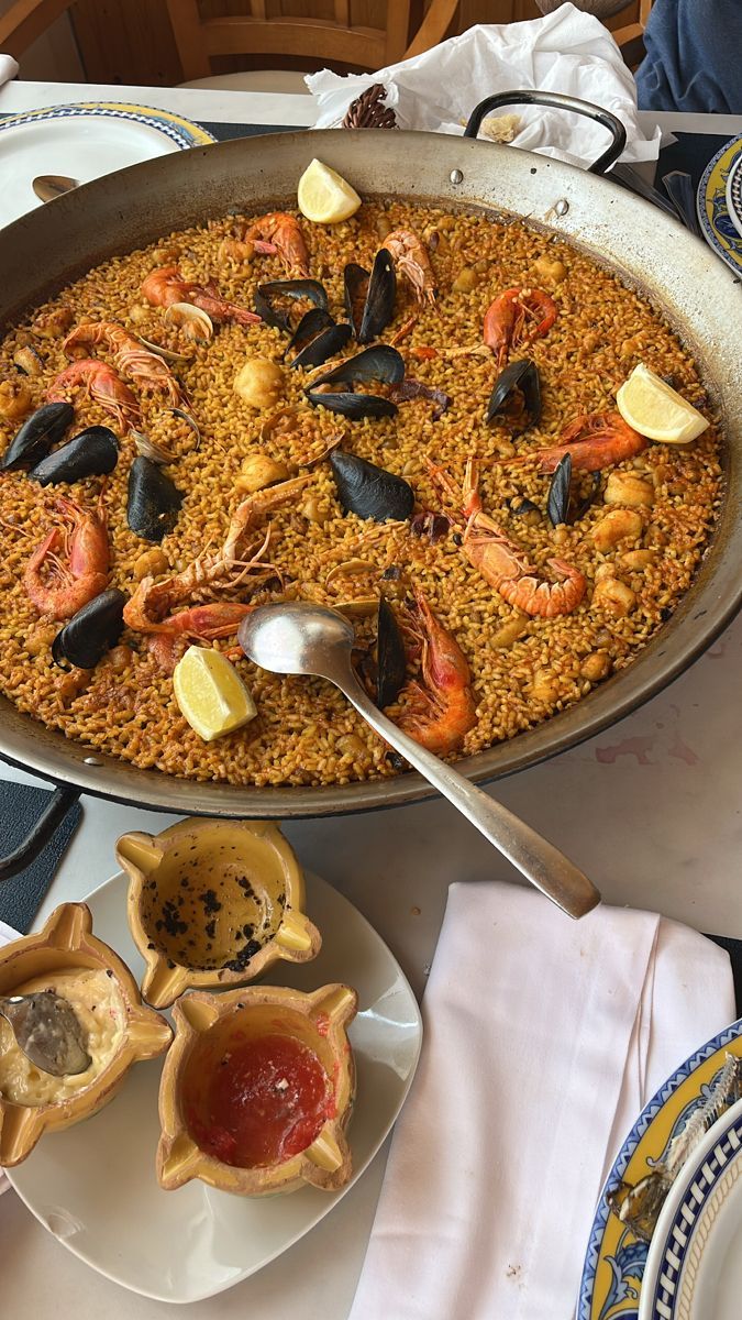 A seafood paella with prawns, mussels and lemon wedges on a restaurant table